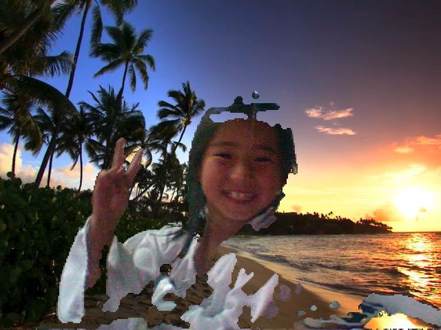 A smiling young girl making a peace sign in a Photo Booth picture with a tropical beach sunset backdrop