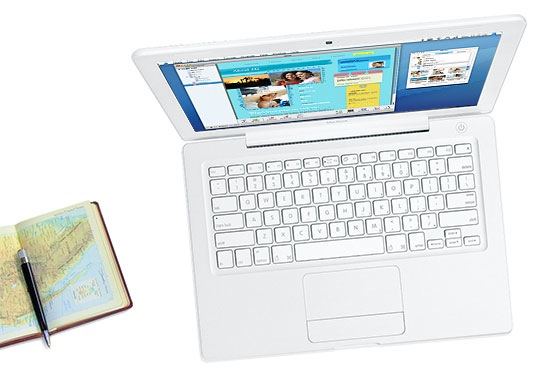 A white MacBook laptop seen from above next to an open journal with a map-printed page and a pen resting on it