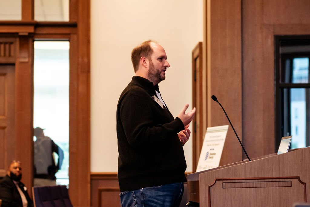Travis Hellstrom speaking at the podium, seen in profile